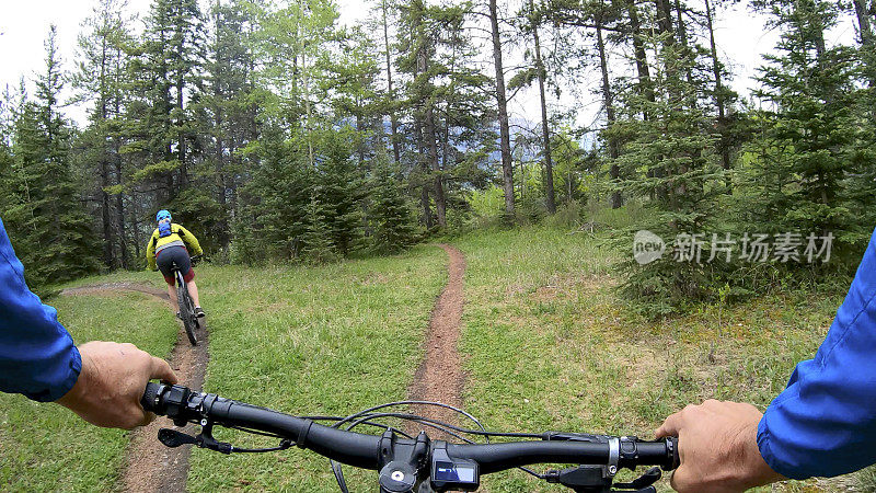 一对夫妇骑着山地电动自行车沿着小路进入森林