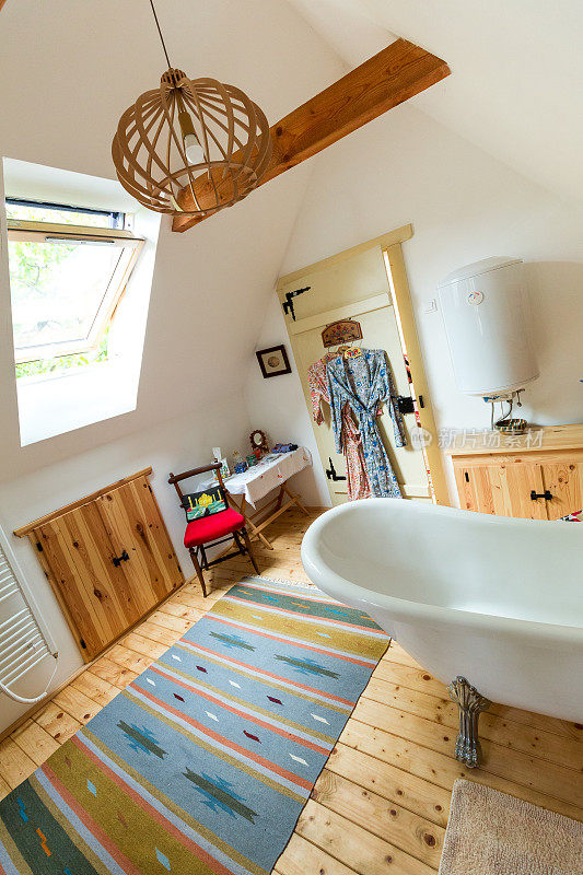 宽敞的浴室内饰有木地板和独立式浴缸