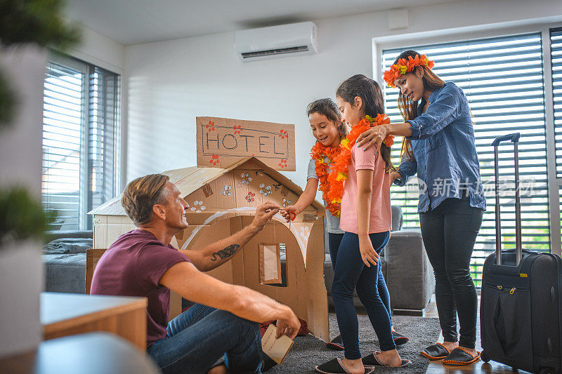 多民族家庭在隔离期间在家玩纸板旅馆