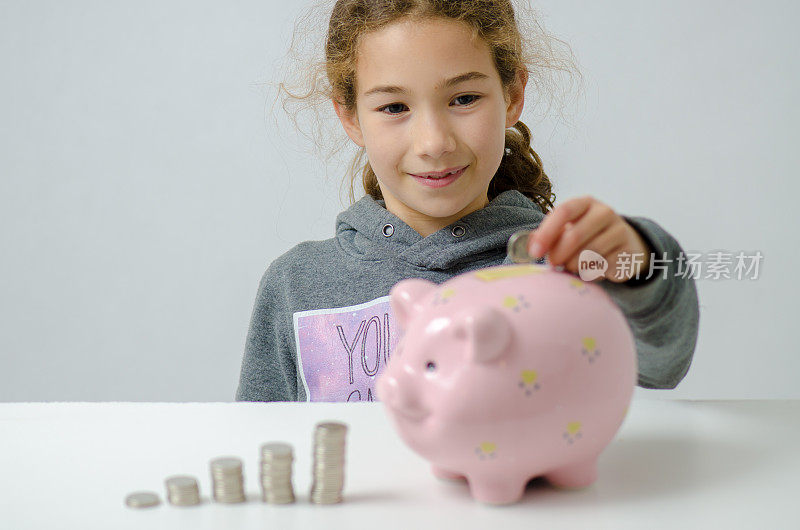 女孩把硬币存进粉红色的存钱罐里