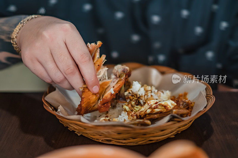 一个面目全非的人在用手吃印尼食物