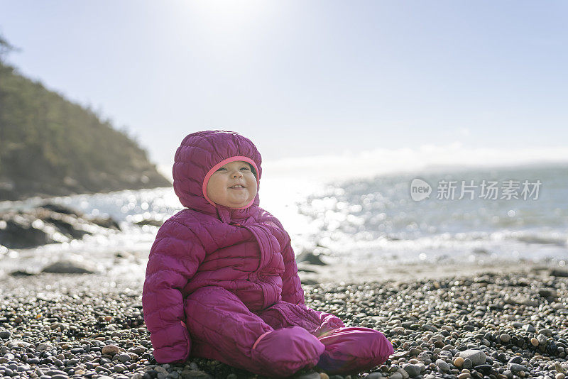 美丽的一岁小女孩独自坐在户外的海滩岩石上