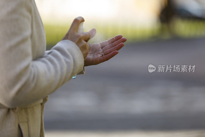 一个女人用消毒洗手液喷在手上