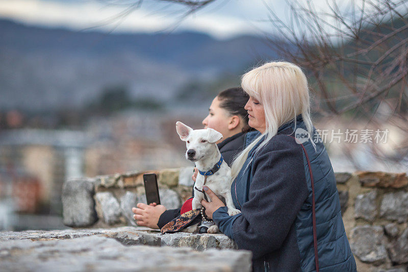 妈妈和十几岁的女儿和他们的杰克罗素梗在旅行中享受风景