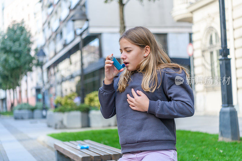 哮喘小女孩在公园里使用吸入器。