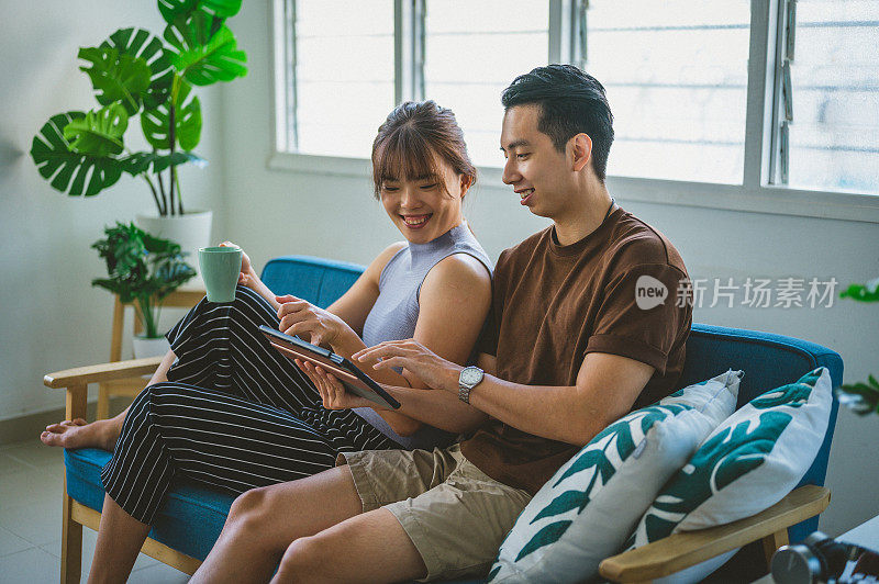 快乐的年轻亚洲夫妇一起使用数字平板电脑在家里网上购物