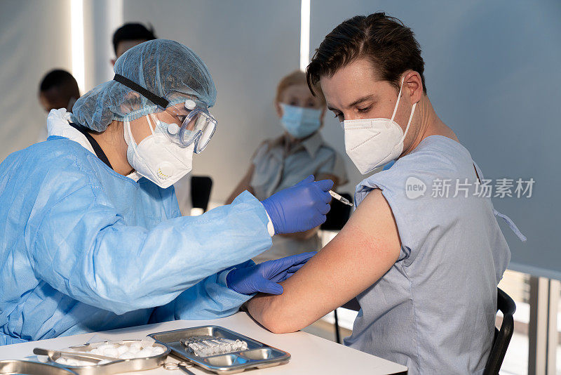 一名医生用注射器向院内白种人注射新冠肺炎疫苗，防止新冠肺炎疫情的爆发