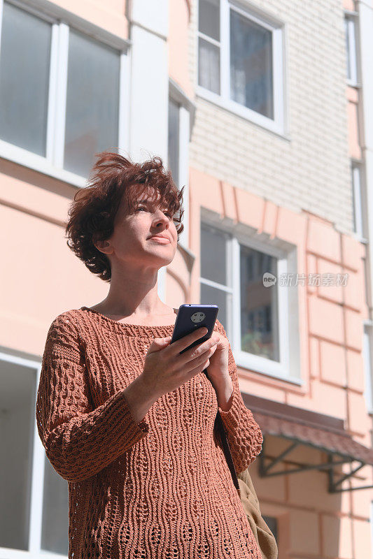 成熟的女人正在寻找城市里的地址。她正在用智能手机上的地图