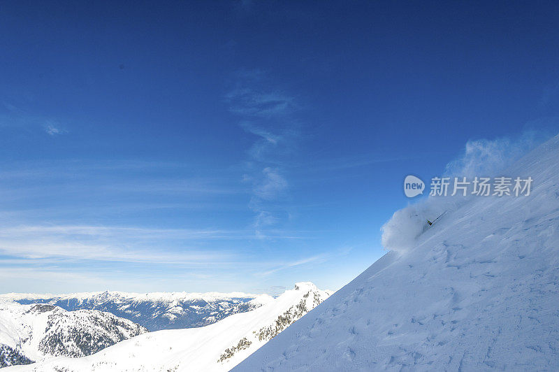 偏远地区的滑雪者从雪山山脊上滑下来