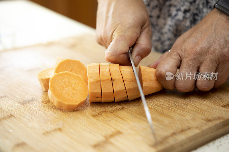 在木制砧板上，女人们用菜刀将去皮的红薯切成薄片