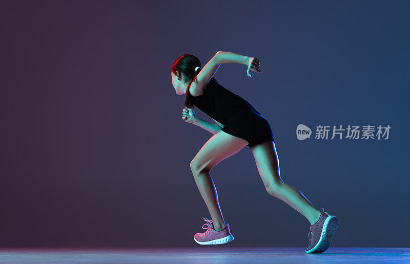 职业运动员的肖像，跑步者训练孤立的梯度蓝色紫色背景在霓虹灯。速度和动力