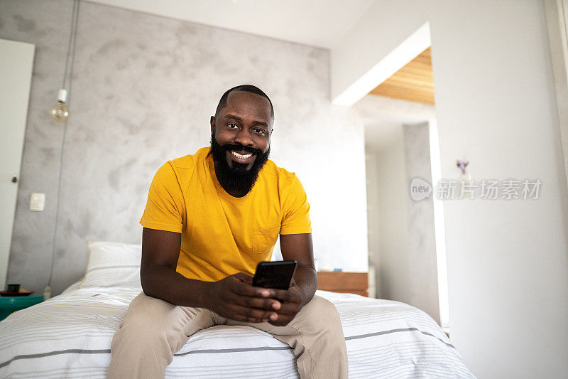 一名中年男子躺在家里的床上使用智能手机