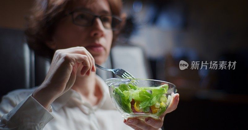 成熟的女人在上班时吃新鲜的蔬菜沙拉