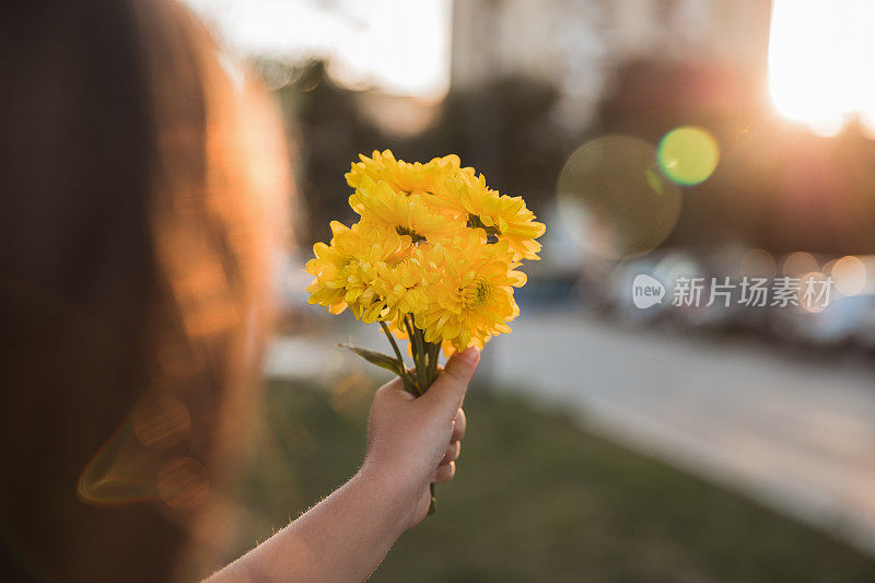 一个年轻的女孩手捧一束黄色的花