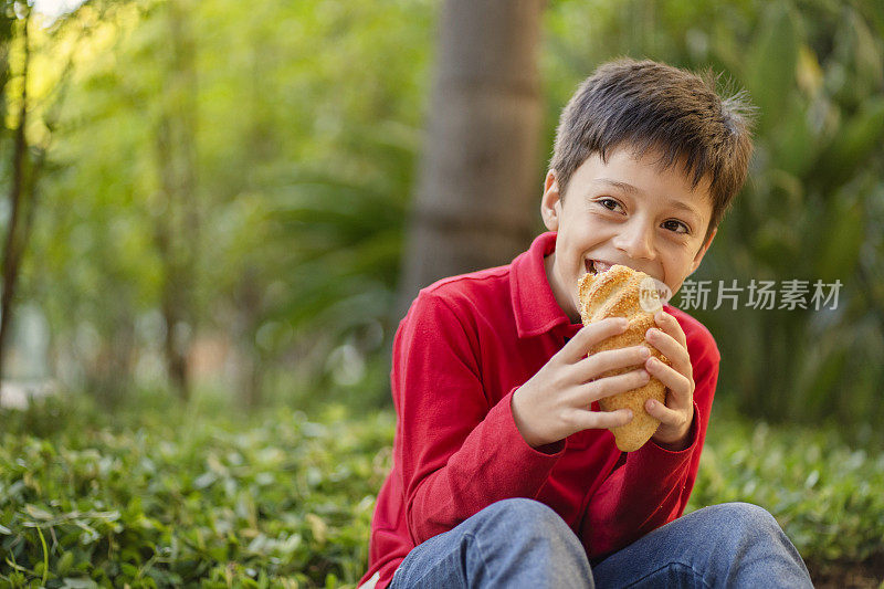 在绿色背景下吃面包的男孩