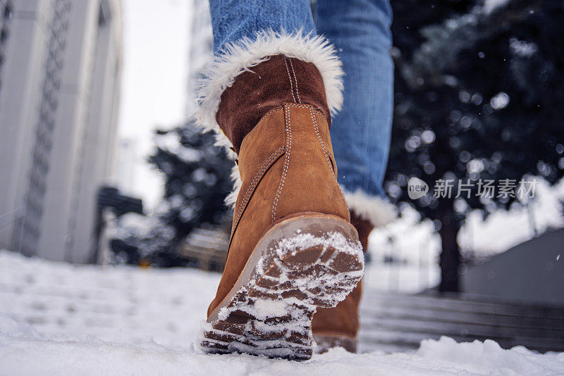 低角度的观点，妇女的靴子走在雪地上