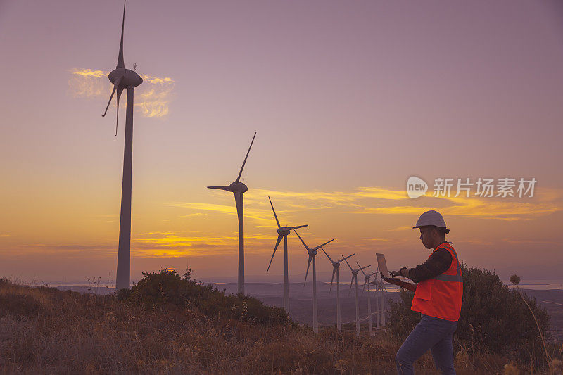 日落时分，年轻的维修工程师在风力发电厂工作。