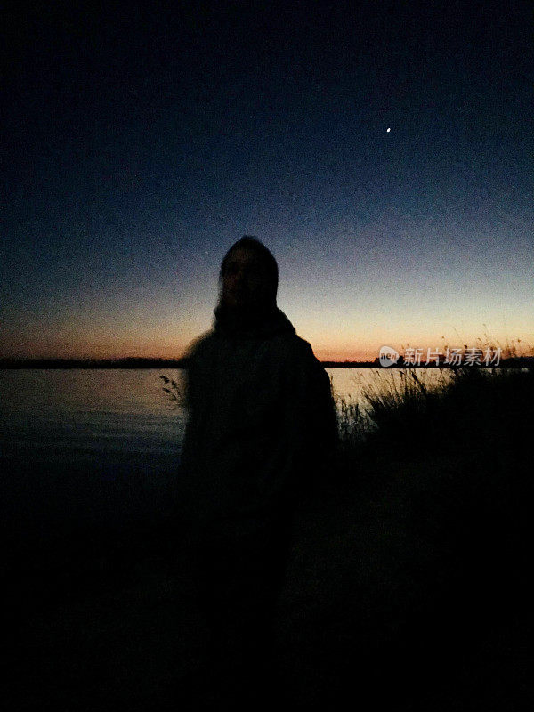黄昏时分，一个男人的剪影站在河边