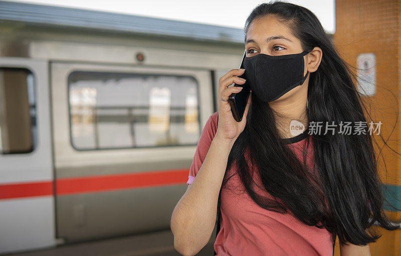 印度一名年轻女子在地铁站等地铁时用手机聊天。