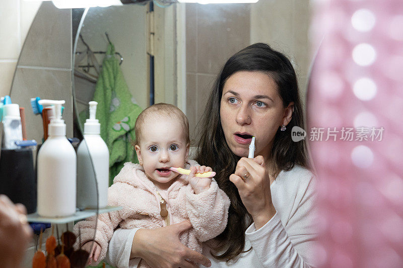 母亲和女儿一起刷牙。