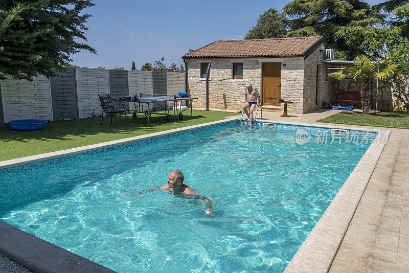 两个成熟的男人在别墅后院的游泳池里游泳