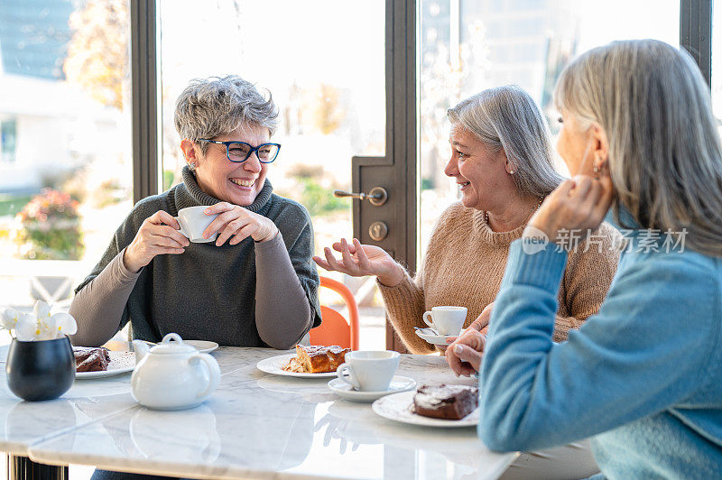 一群老年妇女在自助餐厅吃早餐，三位退休的女性朋友在庆祝周年纪念日，成熟的女性在喝茶和咖啡，吃蛋糕