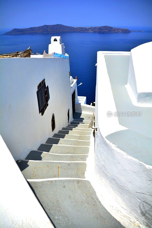 欧洲希腊圣托里尼岛的费拉，白色的下行小巷，带楼梯，可以看到夏天的地中海