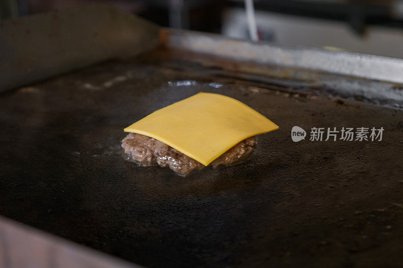 奶酪牛肉饼在烤架上滋滋作响