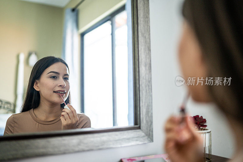 年轻女子在家里的卧室里化妆