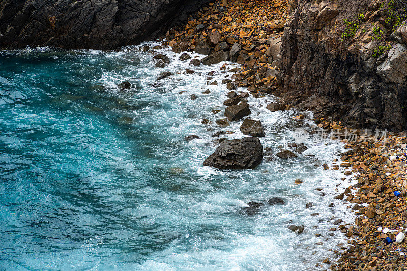 海浪拍打着海滩上的岩石，海水随着阳光飞溅到天空。一个宁静的越南孔岛，是越南海岛的天堂