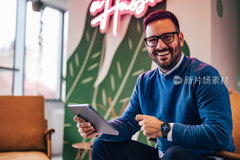 一个微笑的商人戴着眼镜使用数码平板电脑的画像。