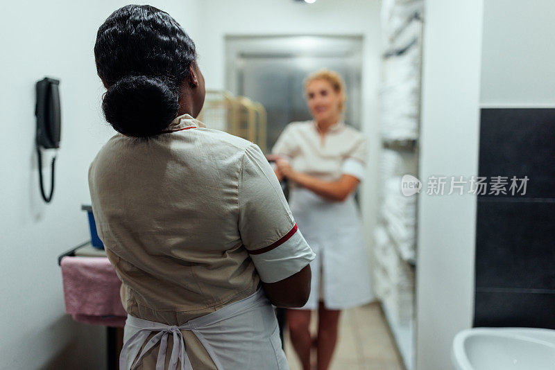 罕见的非裔酒店女服务员在洗衣房面对金发同事的照片