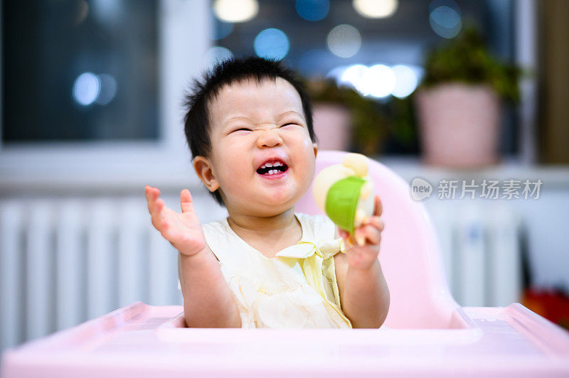 亚洲可爱的小婴儿坐在餐厅的婴儿餐椅上