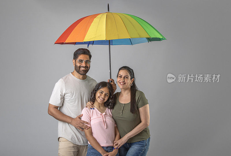 父母和女儿撑着白色背景的雨伞