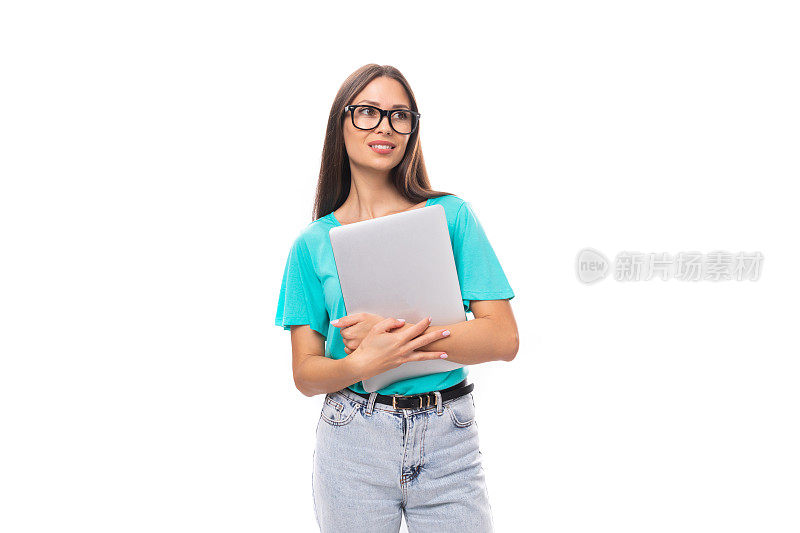 年轻迷人的欧洲女人，黑色长发，穿着蓝色t恤，正在用笔记本电脑远程学习