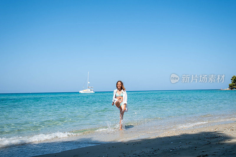 女孩在海里玩，溅起她的脚