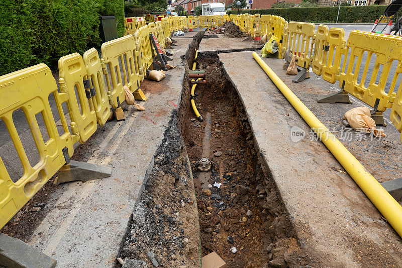 英国的道路工程正在挖掘当地的柏油路面，以修复地下的公用管道，并设置安全屏障和标志