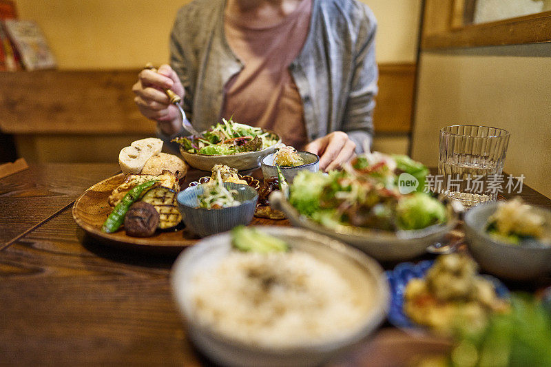 一位亚洲妇女在素食餐厅吃素食午餐。