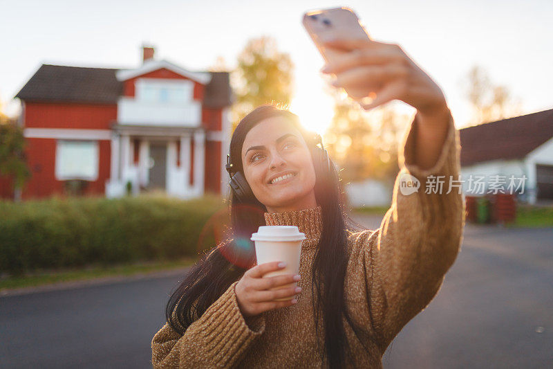 美丽的年轻女子在郊区户外自拍，听音乐