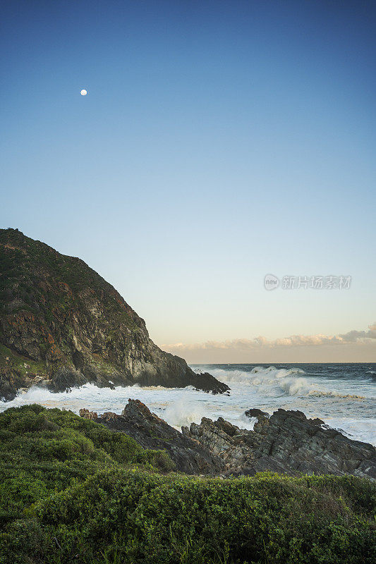 黄昏时分，海浪冲击着风景优美的岩石海岸线