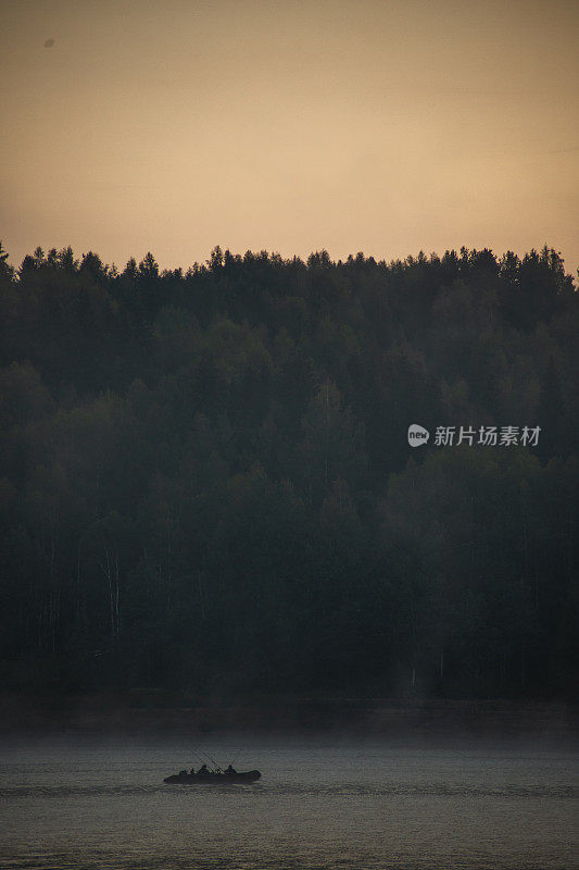 清晨，夏洛特的人们乘着小船在雾蒙蒙的湖面上垂钓，背景是日出