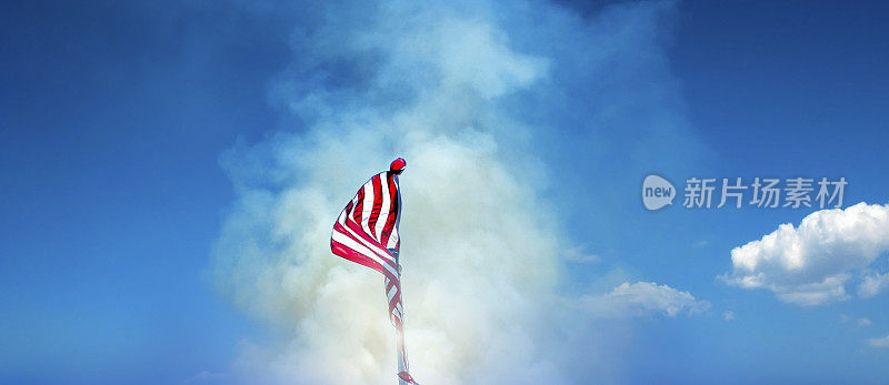 在烟雾弥漫的天空中，旗杆上飘扬着美国国旗
