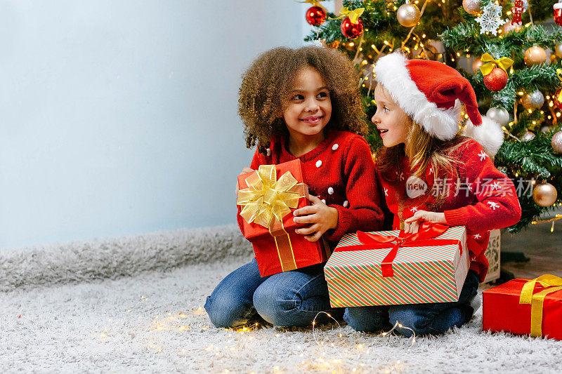 女朋友的女孩们开心地拥抱着圣诞树旁送给彼此的珍贵圣诞礼物