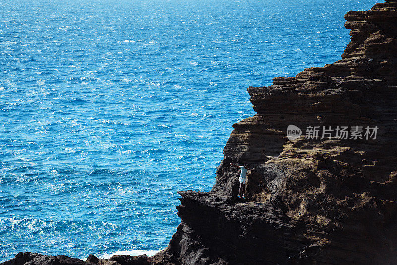 爱冒险的人在俯瞰大海的岩石山小径上徒步旅行