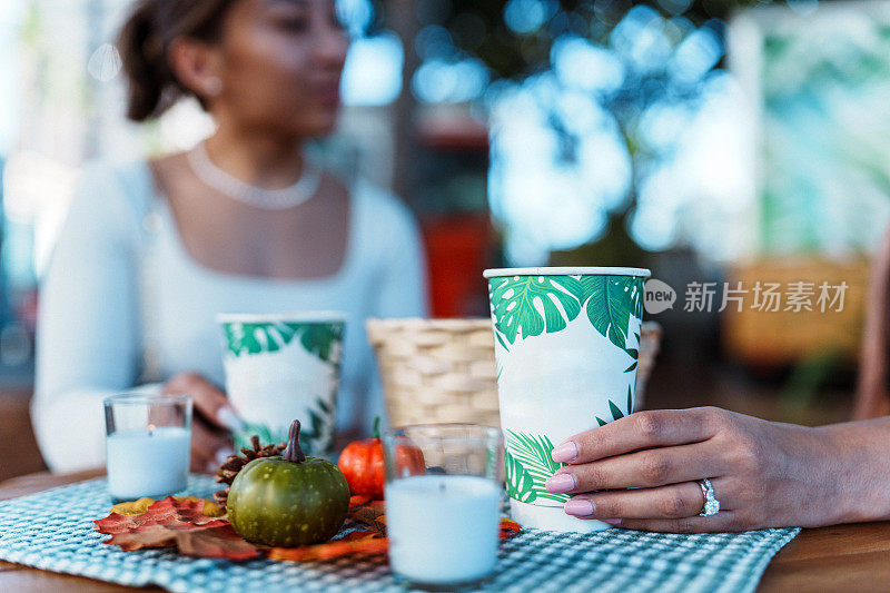 年轻女子端着咖啡坐在外面