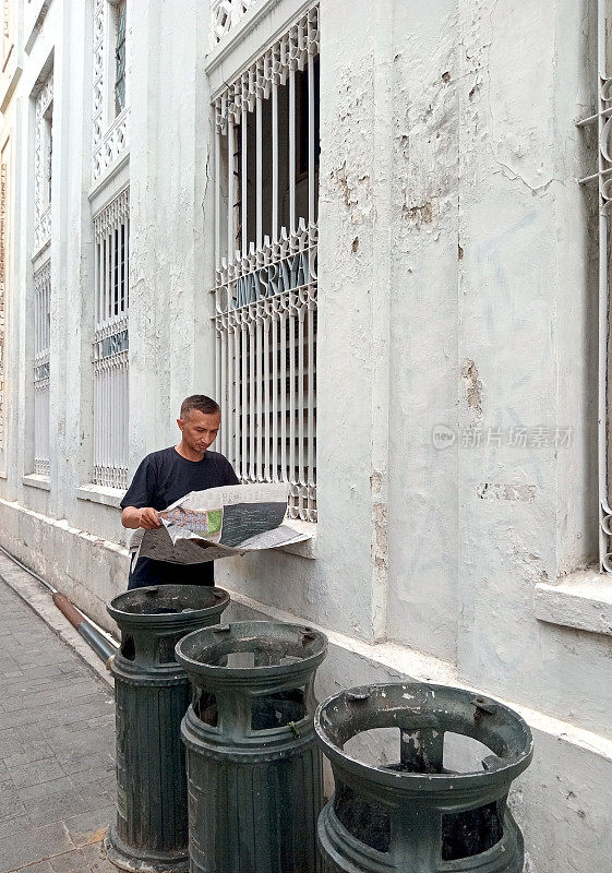 户外健康——一个男人在城市街道上看报纸。