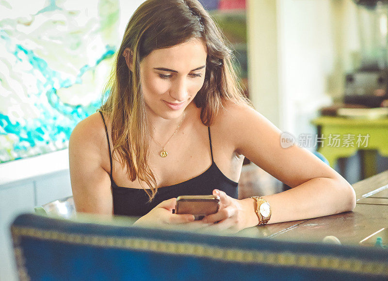 漂亮的年轻女子穿着夏装在沙发上玩手机