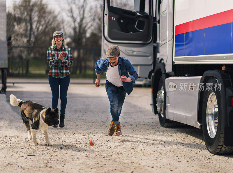 一对卡车司机夫妇在旅途中休息一下，和他们的狗一起玩