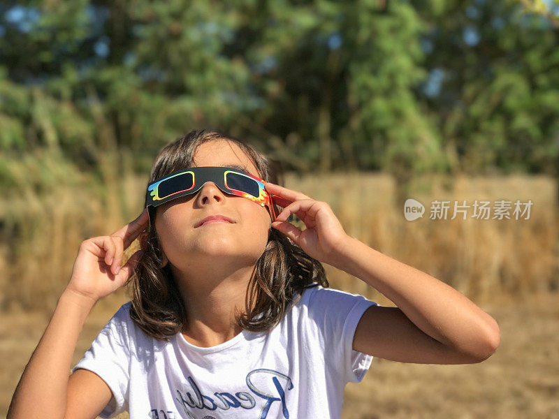 一个小女孩在日食期间在一个国家公园看太阳，家庭户外活动