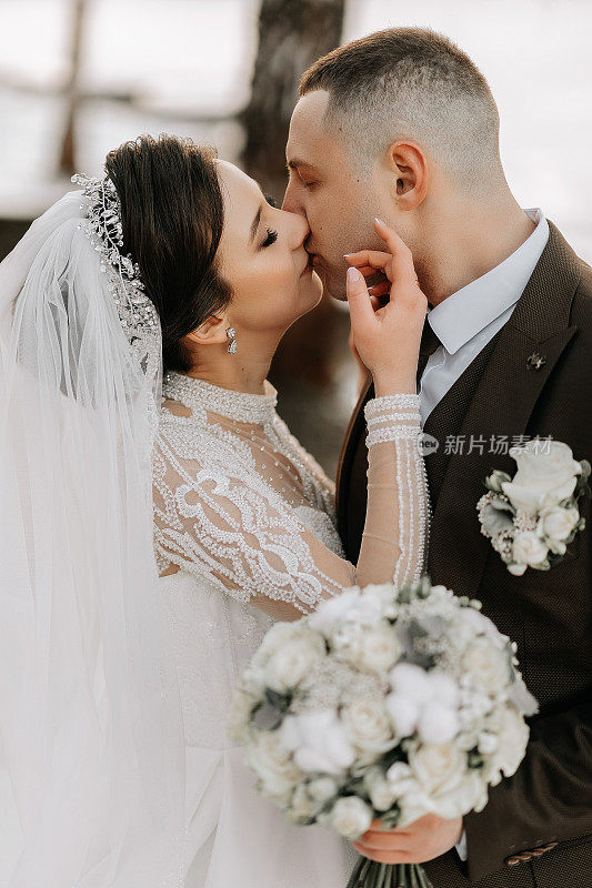 新娘和新郎的结婚照。冬天在大自然中漫步。新娘和新郎拥抱亲吻。精致的衣服